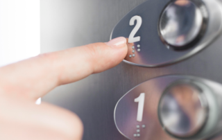 Hand touching braille figure of elevator